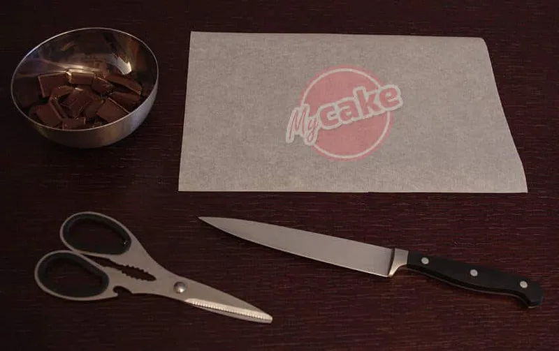 Le matériel pour réaliser un cornet de pâtisserie : papier sulfurisé, couteau, ciseaux et chocolat